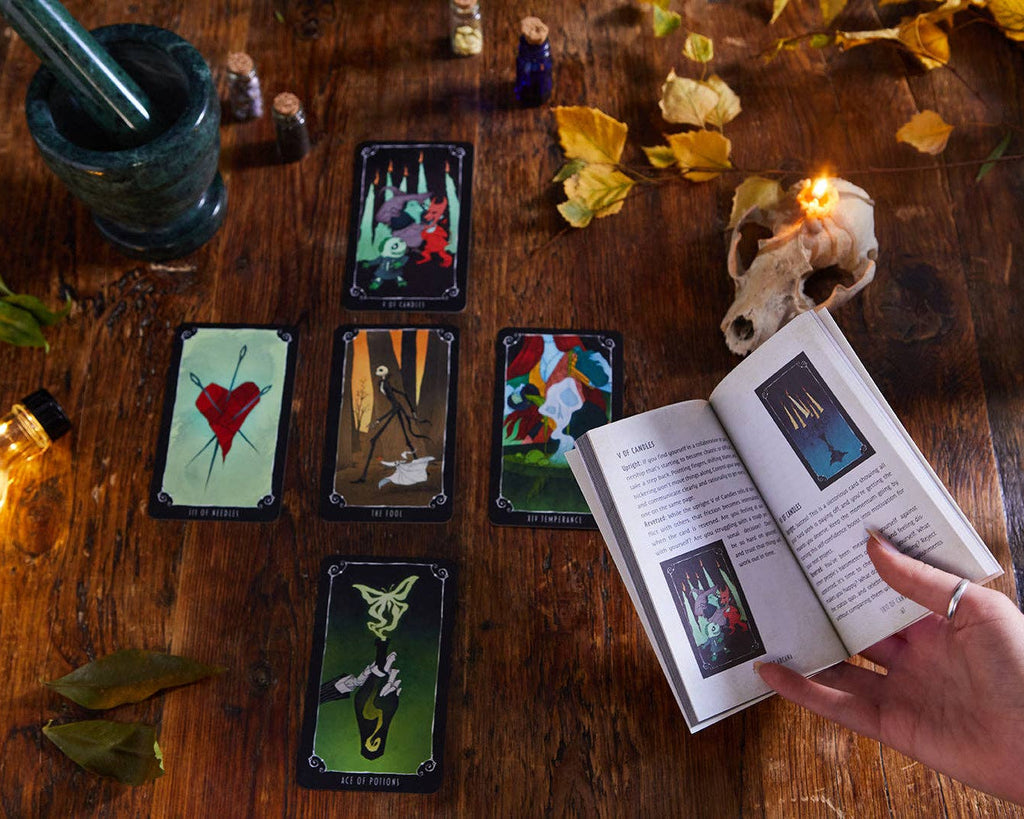 Tarot cards on a wooden table with a book and candles, creating a mystical atmosphere.