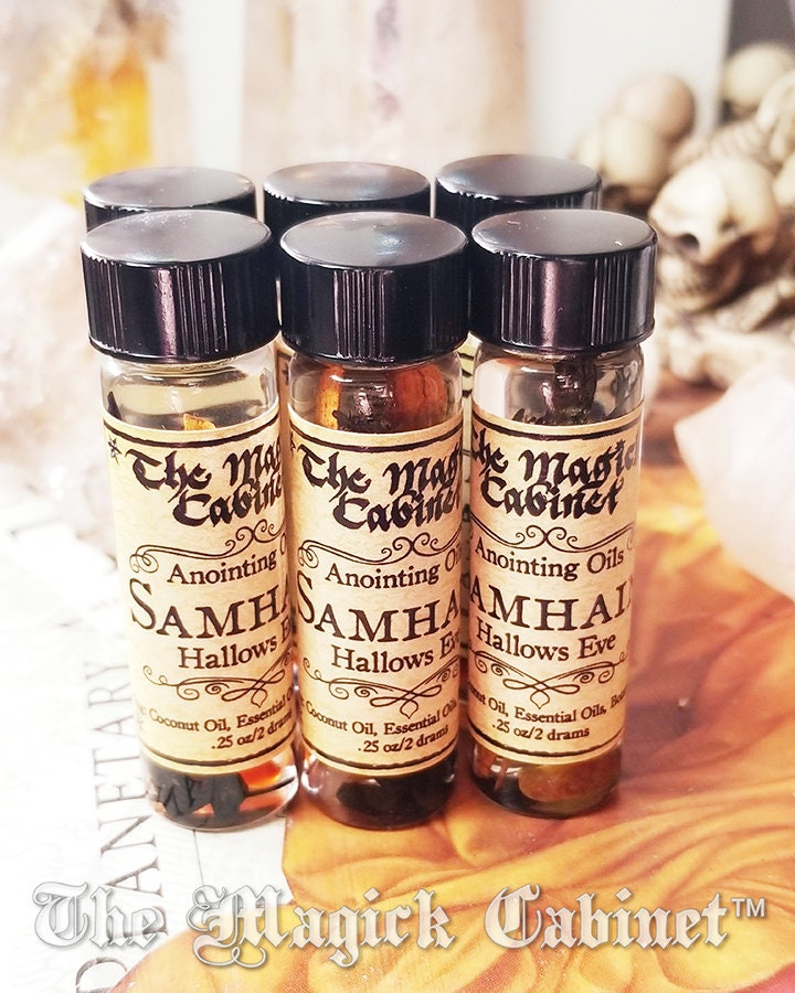 Four small bottles of 'The Magick Cabinet' Samhain oils on a textured surface.