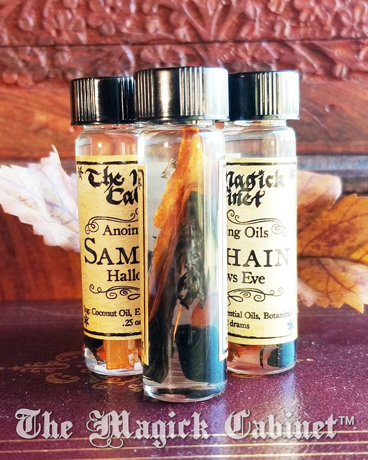 Three small glass bottles with labels on a wooden surface, featuring 'The Magick Cabinet' branding.